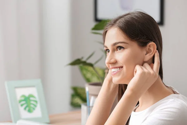 Young woman with hearing aid at home