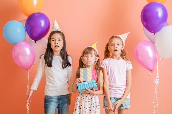 Zaskoczone dziewczyny z urodziny balony powietrza i prezenty na tle koloru — Zdjęcie stockowe