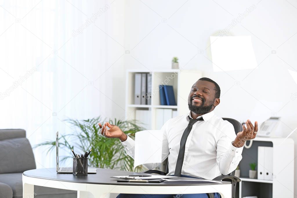 Handsome African-American man meditating in office