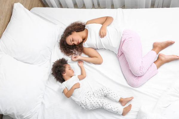 Niña afroamericana con madre durmiendo en la cama —  Fotos de Stock