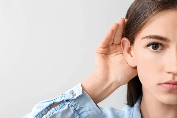 Młoda kobieta z problem słuchu na jasnym tle — Zdjęcie stockowe