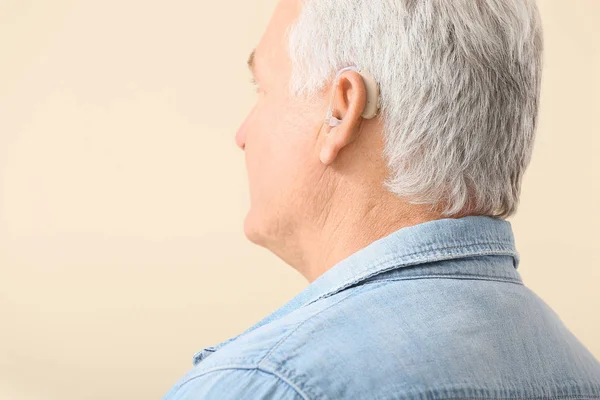 Starší muž s naslouchátkem na světlém pozadí — Stock fotografie