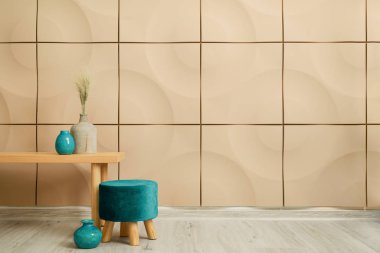 Renkli duvarın yanında masa ve vazolarla süslü bir pouf.