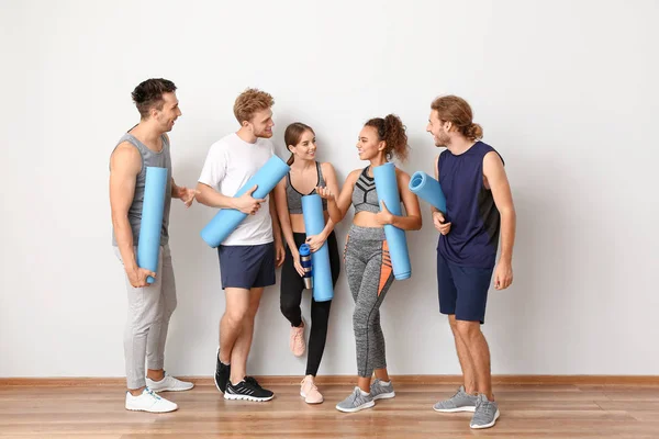 Groep mensen met yogamatten bij lichte wand — Stockfoto