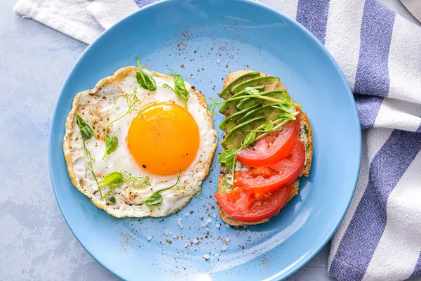 Plate with tasty avocado sandwich and fried egg on table — Stock Photo, Image