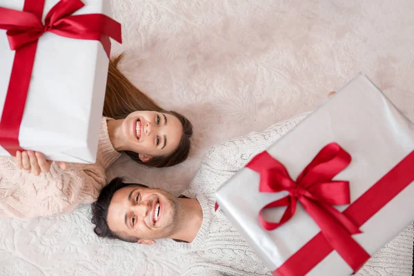 Jovem casal feliz com presentes de Natal deitado no chão, vista superior — Fotografia de Stock