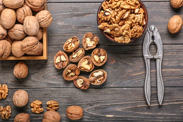 Nussknacker mit leckeren Walnüssen auf Holzgrund — Stockfoto