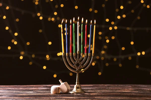 Menorah med ljus för Hanukkah och dreidels på bordet mot mörk bakgrund — Stockfoto