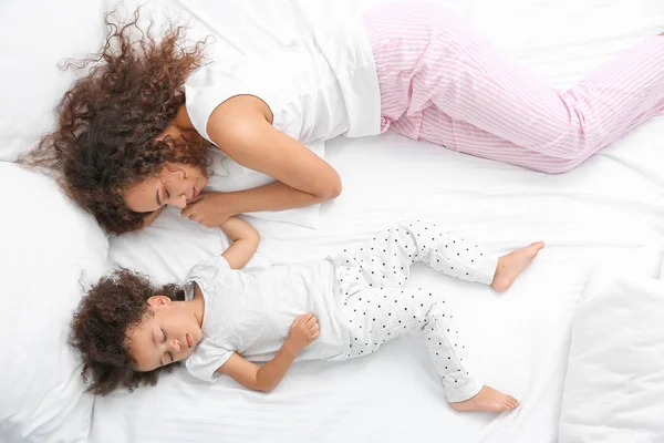 Kis afro-amerikai lány anya alszik az ágyban — Stock Fotó