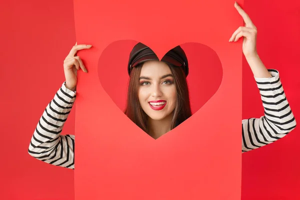Bella giovane donna in possesso di carta con cuore tagliato su sfondo a colori. Festa di San Valentino — Foto Stock