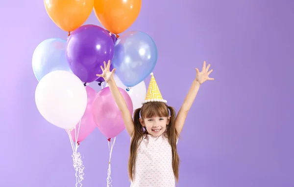 Щаслива маленька дівчинка з повітряними кулями на кольоровому фоні — стокове фото