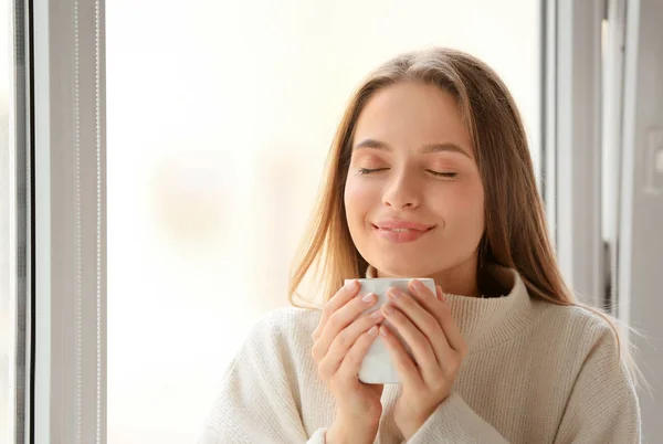 Mujer joven con taza de té caliente descansando en casa — Foto de Stock