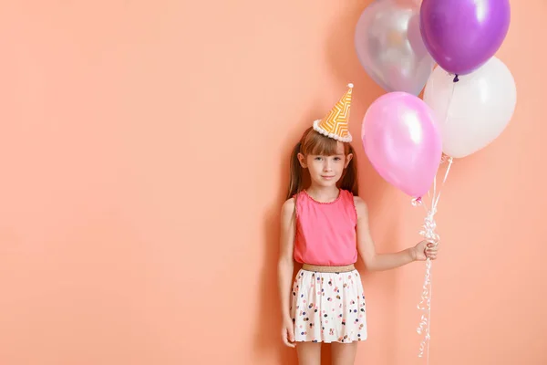Malá holka s narozeninovými vzduchové balónky na barevném pozadí — Stock fotografie