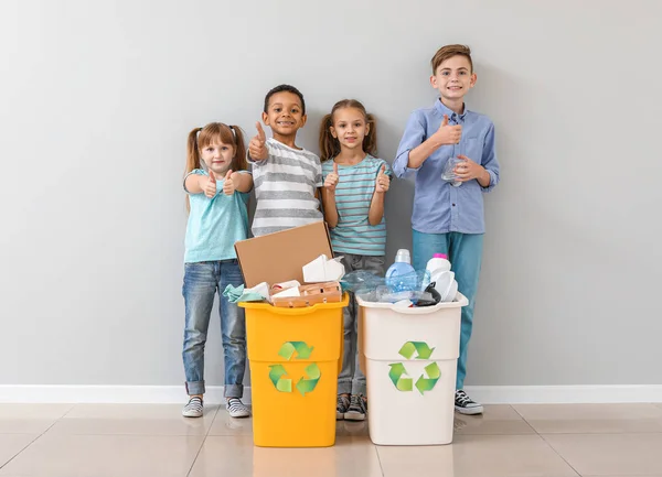 Crianças pequenas e recipientes com lixo perto da parede de luz. Conceito de reciclagem — Fotografia de Stock