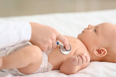 Çocuk doktoru klinikte şirin bir bebeği muayene ediyor.
