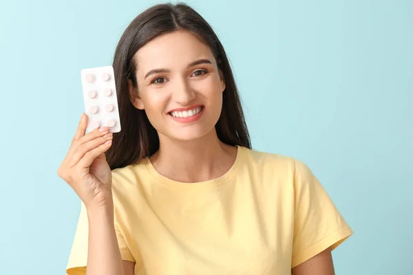 Young woman with pills on color background — Stock Photo, Image