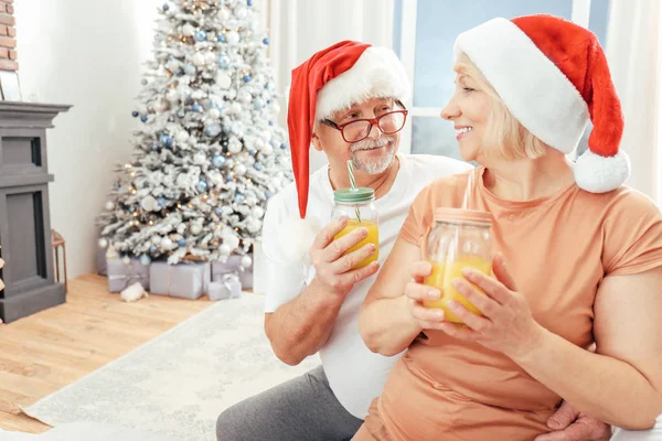 Happy mature couple drinking juice on Christmas eve at home — Stock Photo, Image