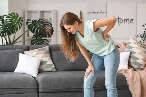 Young woman suffering from back pain at home — Stock Photo, Image
