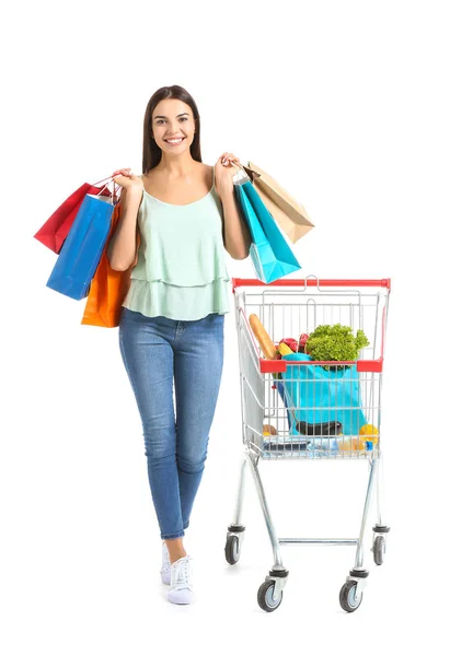 Young woman with shopping cart and bags on white background — Stock Photo, Image