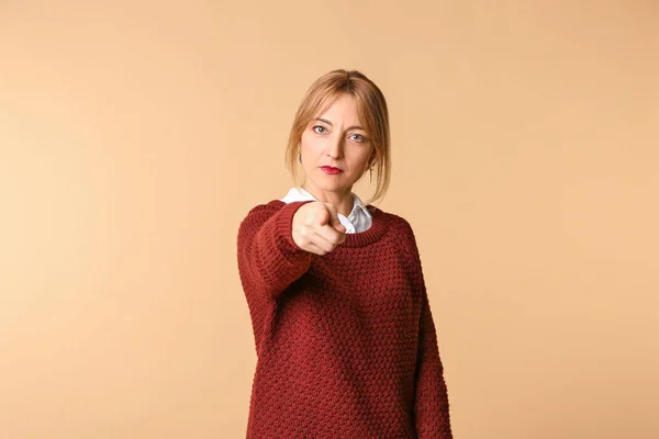 Mature woman pointing at viewer against color background — Stock Photo, Image