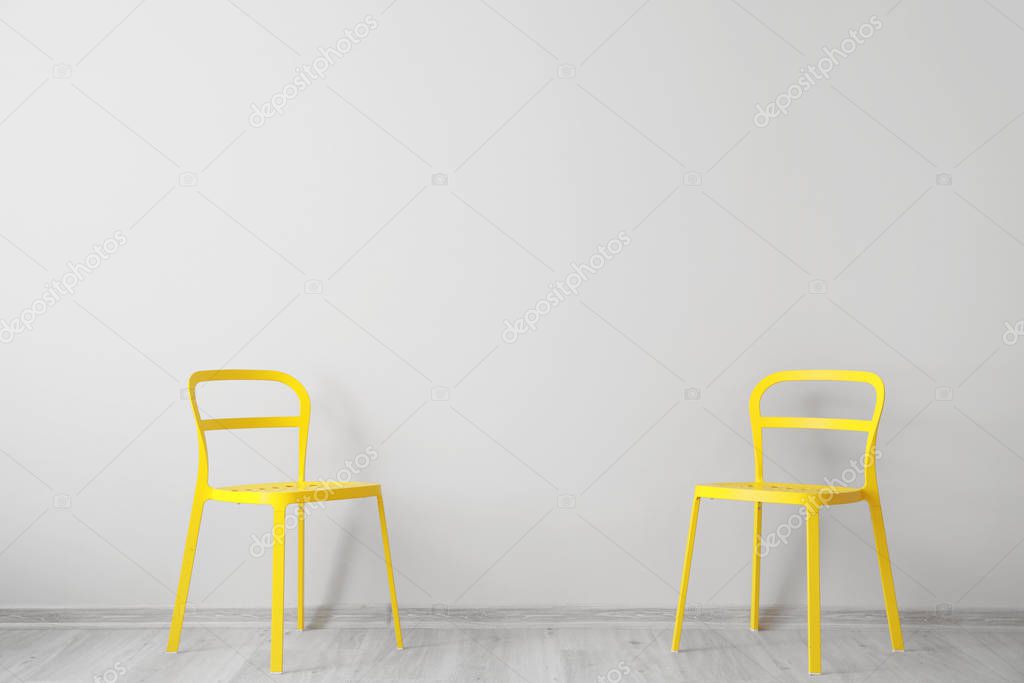 Stylish chairs near light wall