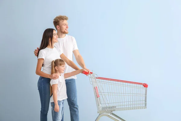 Familia con carrito de compras vacío sobre fondo de color —  Fotos de Stock
