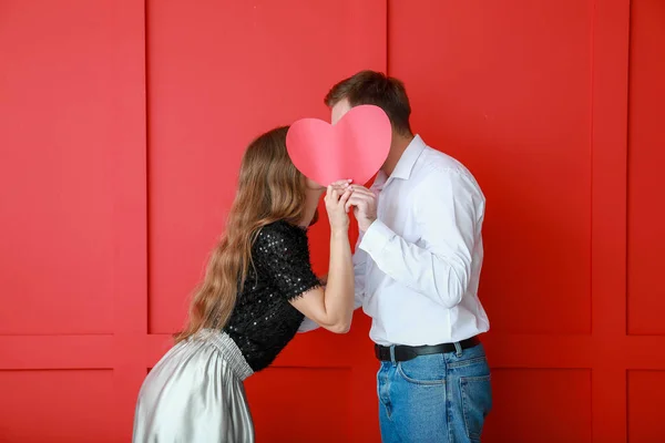 Šťastný mladý pár s červeným srdcem na pozadí barvy. Valentýnská oslava — Stock fotografie
