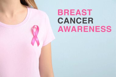 Pembe kurdeleli ve göğüs kanseri farkındalığını mesaj atan genç bir kadın.