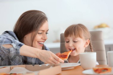 Mutlu anne ve küçük kızı evde pizza yiyor