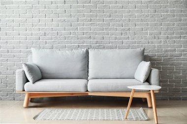 Yumuşak kanepe ve tuğla duvarın yanındaki masa