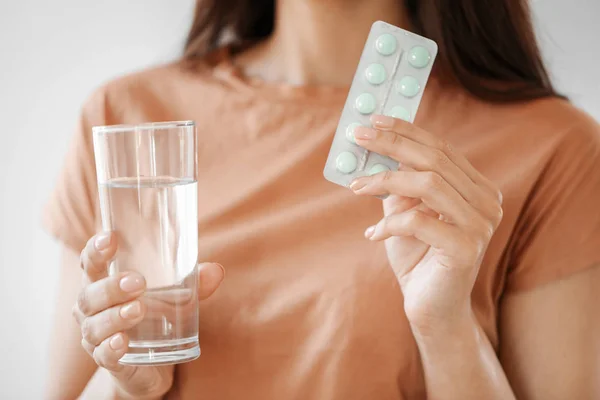 Jeune femme avec des pilules et un verre d'eau, gros plan — Photo