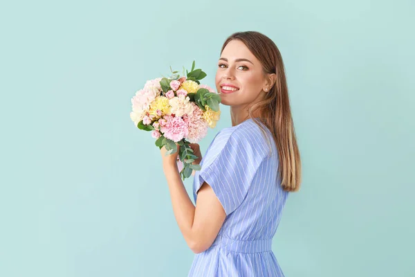 Schöne junge Frau mit einem Strauß Nelkenblumen auf farbigem Hintergrund — Stockfoto