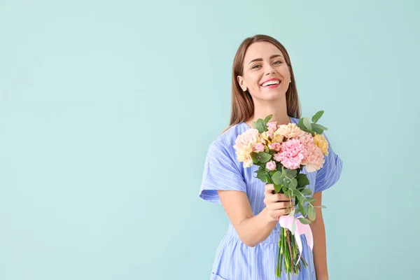 Красива молода жінка з букетом з квітів гвоздик на кольоровому фоні — стокове фото
