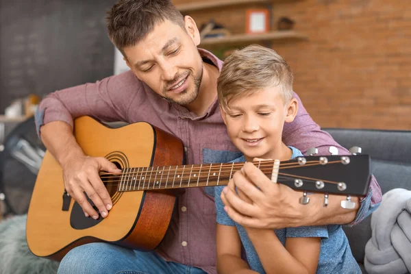 Padre enseñando a su hijito a tocar la guitarra en casa — Foto de Stock