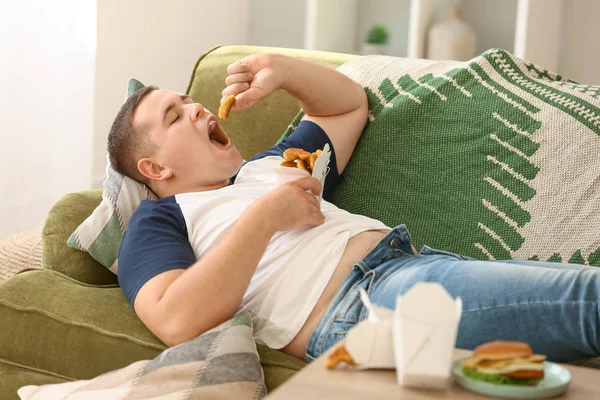 Túlsúlyos férfi egészségtelen ételt eszik otthon. — Stock Fotó