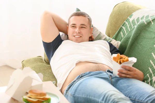Homem com excesso de peso comendo alimentos não saudáveis em casa — Fotografia de Stock