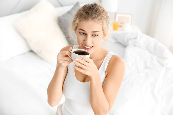 Πρωινό της όμορφης νεαρής γυναίκας πίνοντας καφέ στην κρεβατοκάμαρα — Φωτογραφία Αρχείου