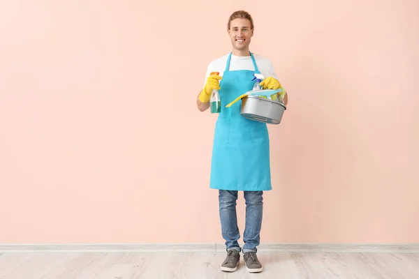 Male janitor with cleaning supplies near color wall — Stock Photo, Image