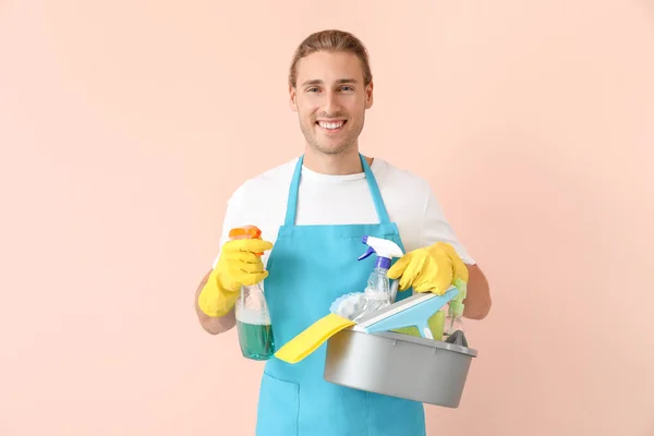 Male janitor with cleaning supplies on color background — Stock Photo, Image