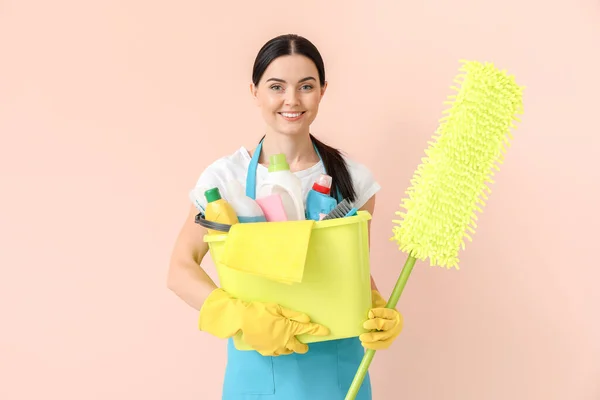 Janitor feminino com suprimentos de limpeza em fundo de cor — Fotografia de Stock