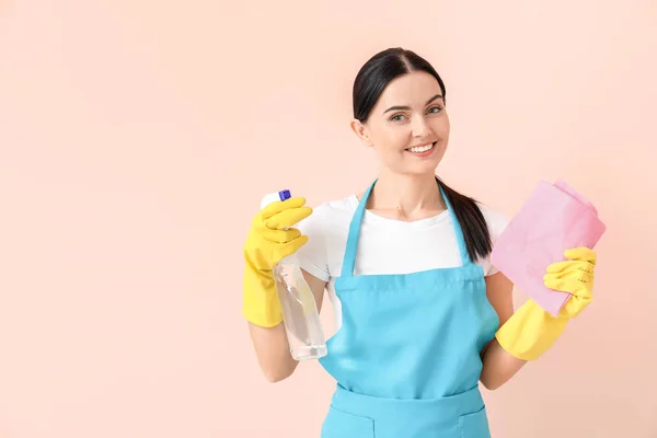 Female janitor with cleaning supplies on color background — Stock Photo, Image