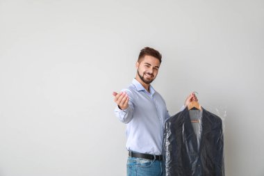 Modern kuru temizlemecinin erkek çalışanı arka planda izleyiciyi davet ediyor
