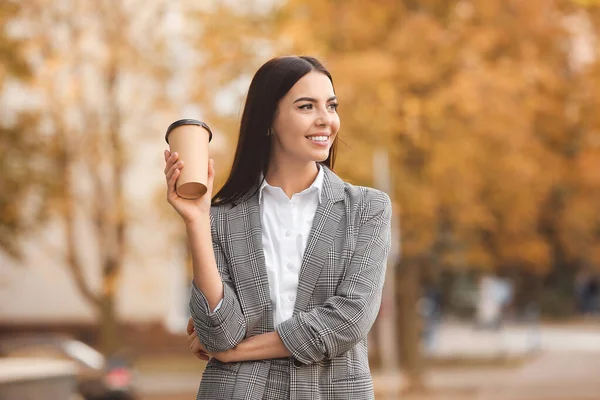 Beautiful young businesswoman with cup of coffee outdoors — Stock Photo, Image