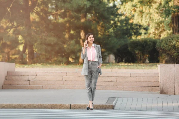 Beautiful young businesswoman crossing road outdoors — Stock Photo, Image