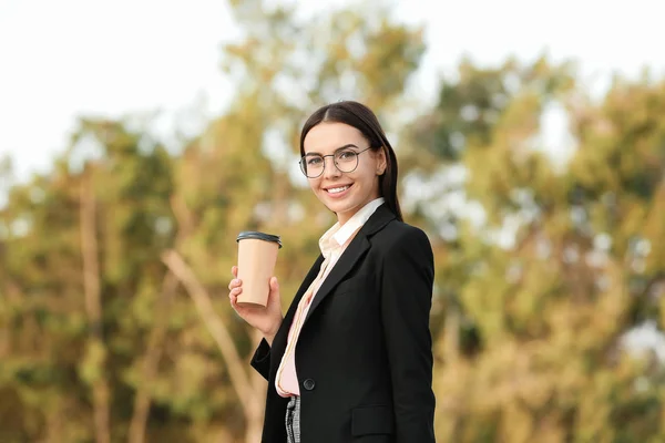 Beautiful young businesswoman with cup of coffee outdoors — Stock Photo, Image