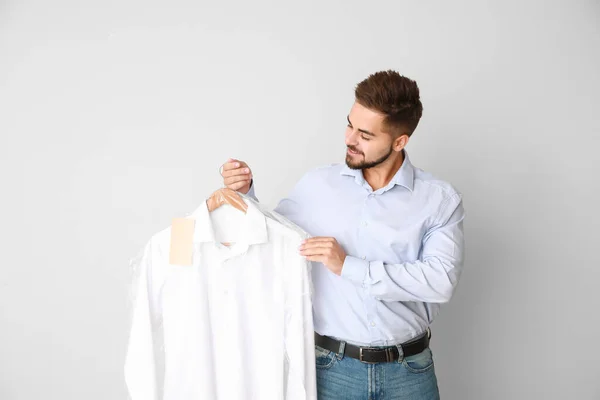 Trabajador masculino de tintorería moderna con ropa sobre fondo claro —  Fotos de Stock