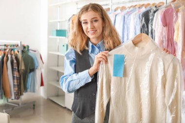 Modern kuru temizlemecide kıyafetleri olan genç bir bayan işçi.