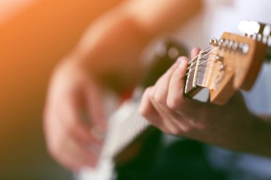 Küçük çocuk evde gitar çalıyor, yakın plan.