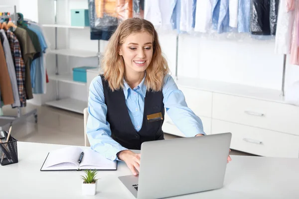 Young female worker sitting at workplace at dry-cleaner's — Stock Photo, Image