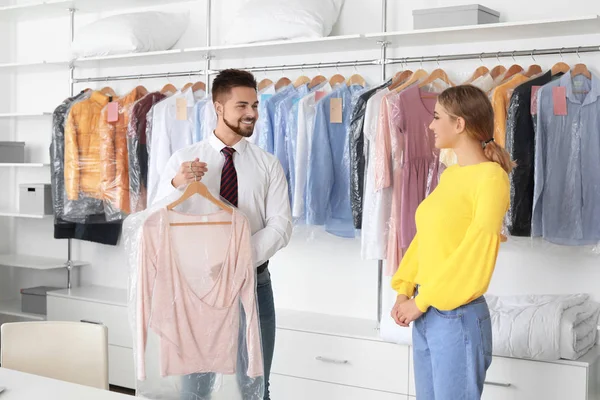 Работник мужского пола показывает клиенту чистую одежду в современной химчистке — стоковое фото